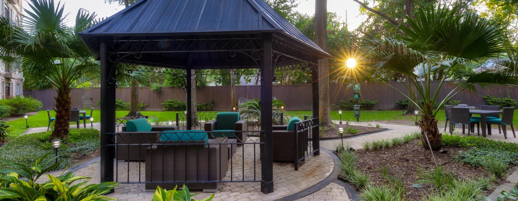 a gazebo in a garden with chairs and tables