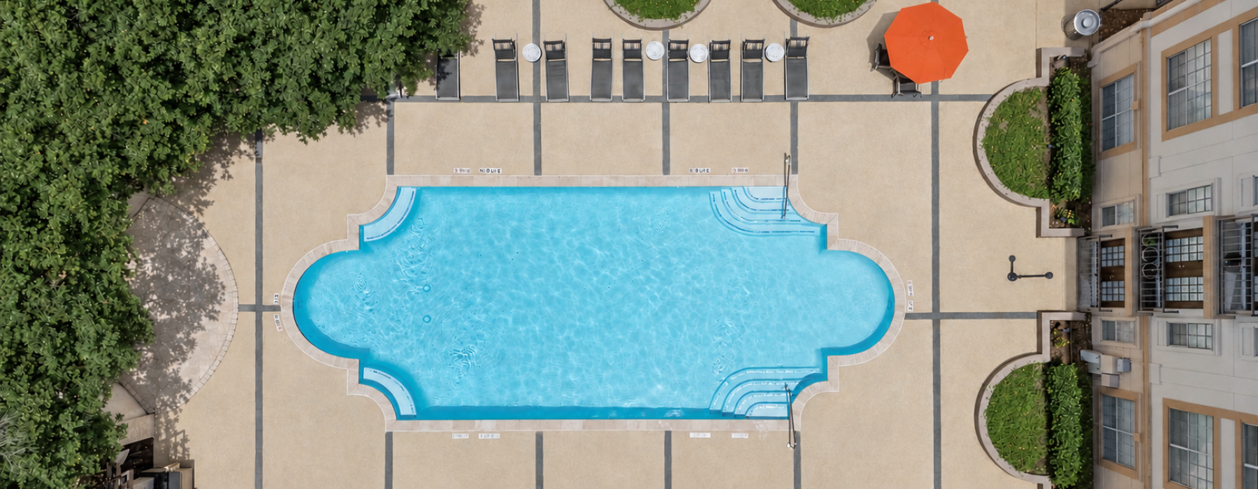 Aerial view of the resort-style pool, lounge seating, and landscaped courtyard at Deerwood Apartments in Houston, Texas.